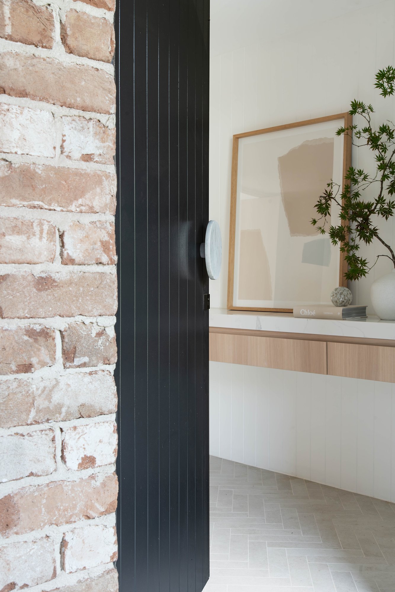 Recycled brick wall meets black fluted timber column with floating American oak joinery and terrazzo flooring.