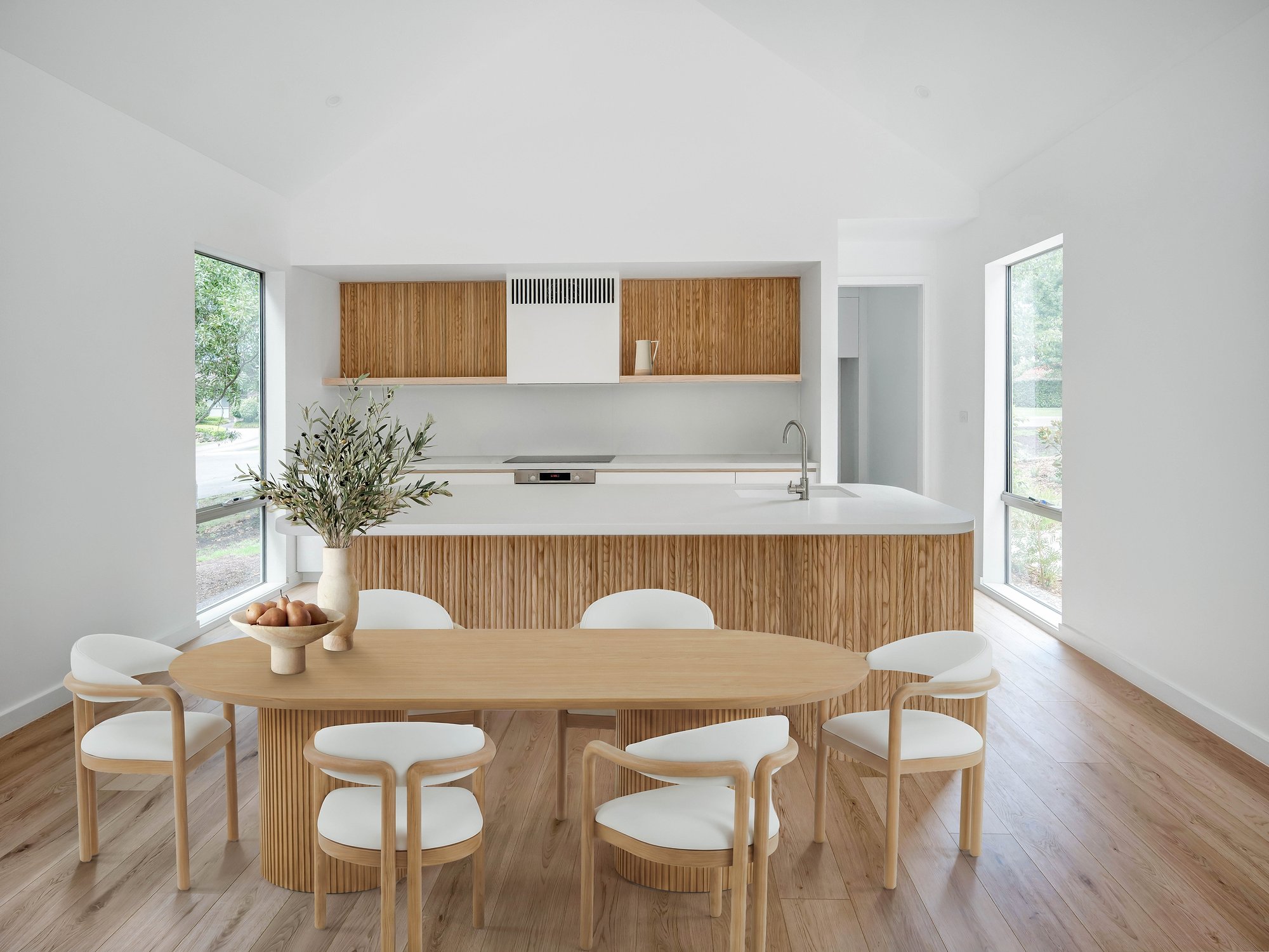 Open-plan kitchen and dining with oak joinery, soft stone benchtop, and hardwood floors