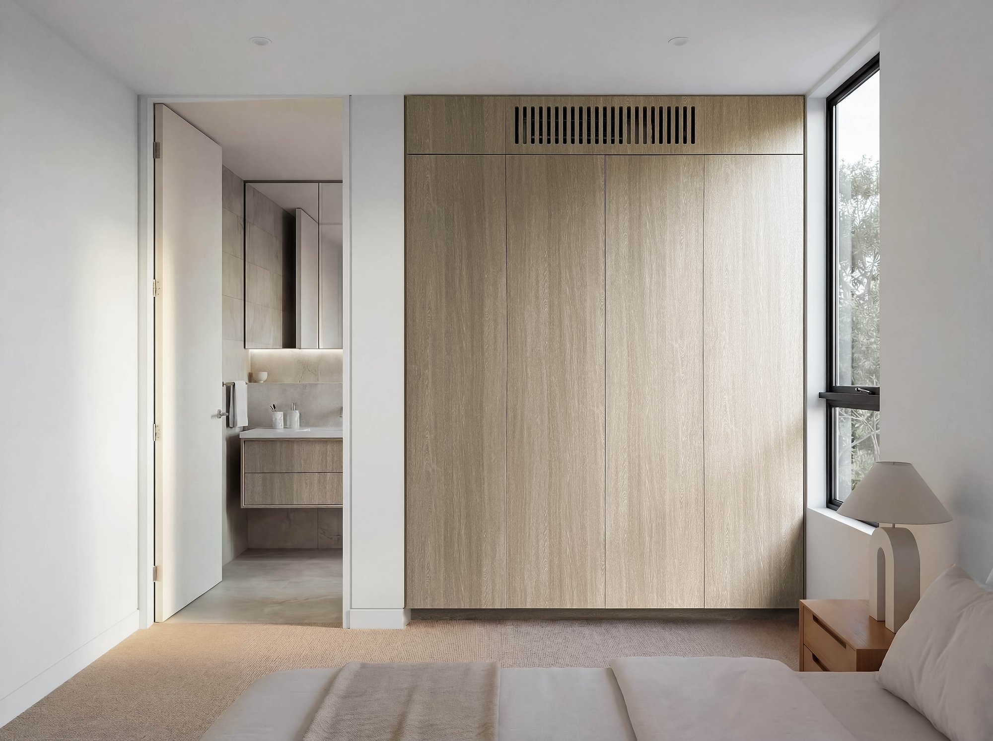 Built-in wardrobes in American oak veneer with integrated storage and ensuite glimpsed beyond white walls.