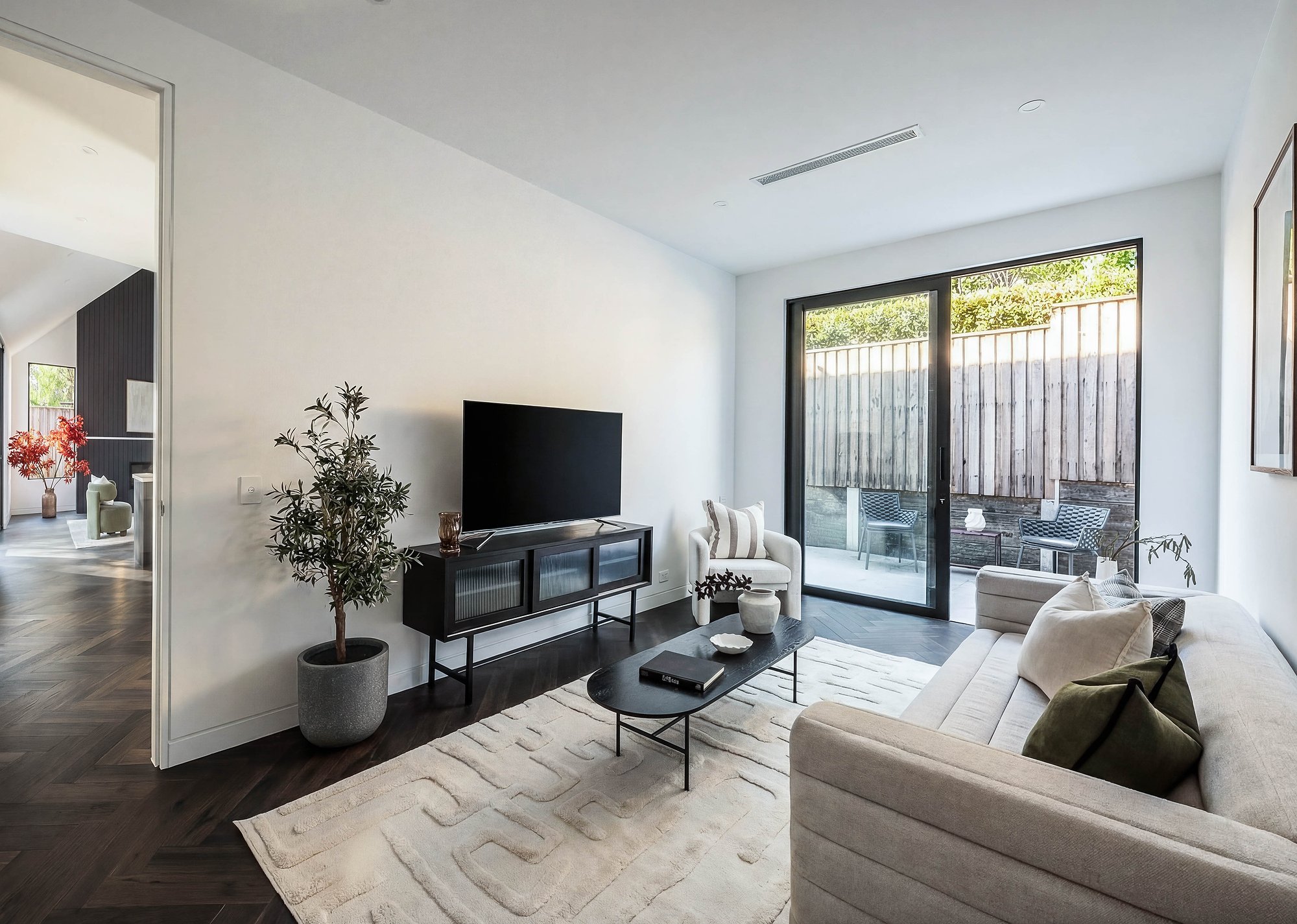 Living room with American oak floors, black steel media console, and sliding doors to private courtyard.