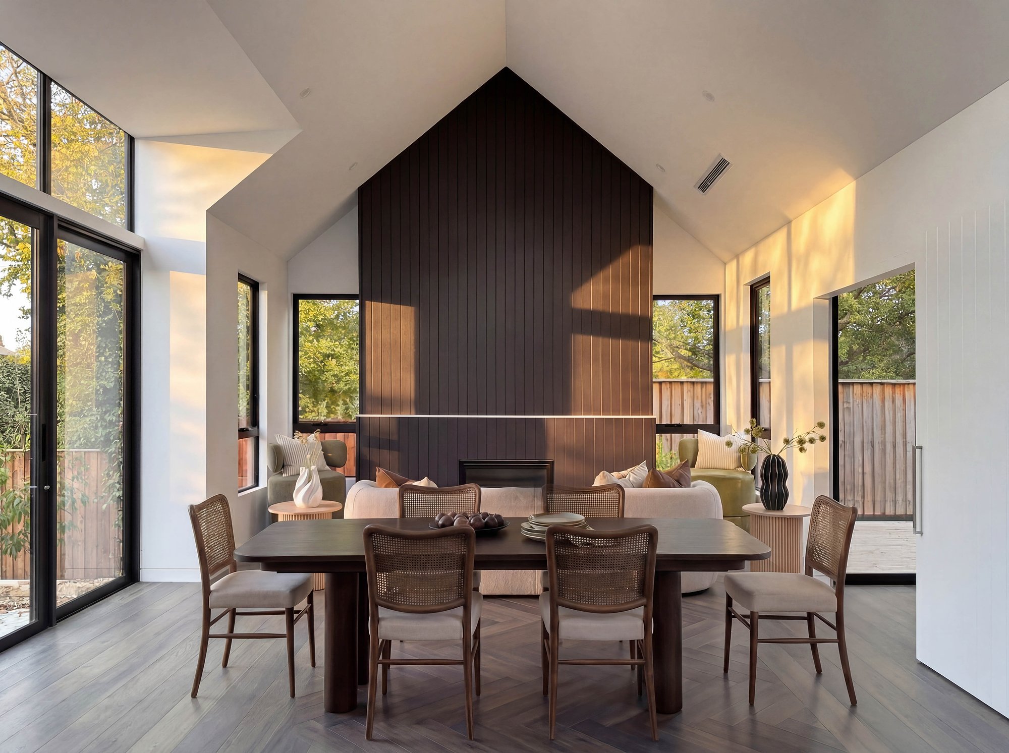 Open dining room with recycled brick fireplace wall, American oak table, and floor-to-ceiling windows overlooking established trees.