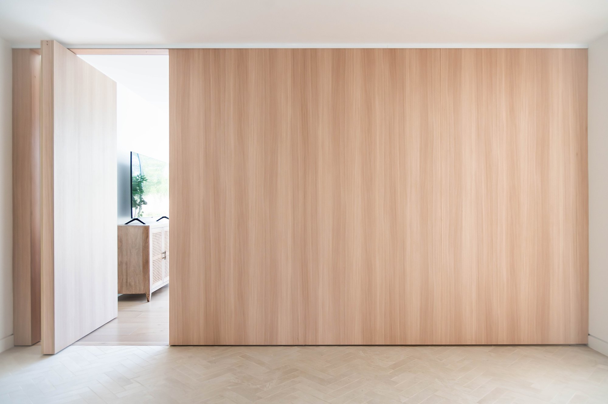 Vertical timber cladding frames an opening to bright interior spaces with polished concrete flooring.